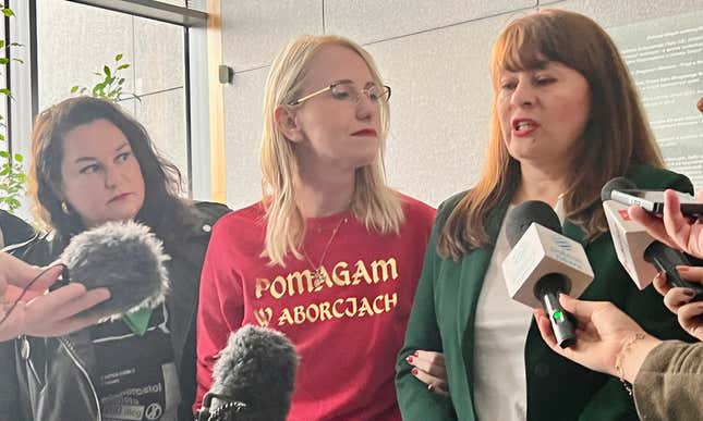 Justyna Wydrzynska, far right, speaks to reporters outside a courthouse in Warsaw amid her trial for illegally aiding an abortion.