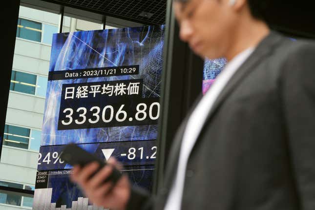 A person walks in front of an electronic stock board showing Japan&#39;s Nikkei 225 index at a securities firm Tuesday, Nov. 21, 2023, in Tokyo. Asian shares were mostly higher on Tuesday after a rally on Wall Street led by gains in Microsoft following its announcement that it was hiring Sam Altman, former CEO of OpenAI, the ChatGPT maker. (AP Photo/Eugene Hoshiko)