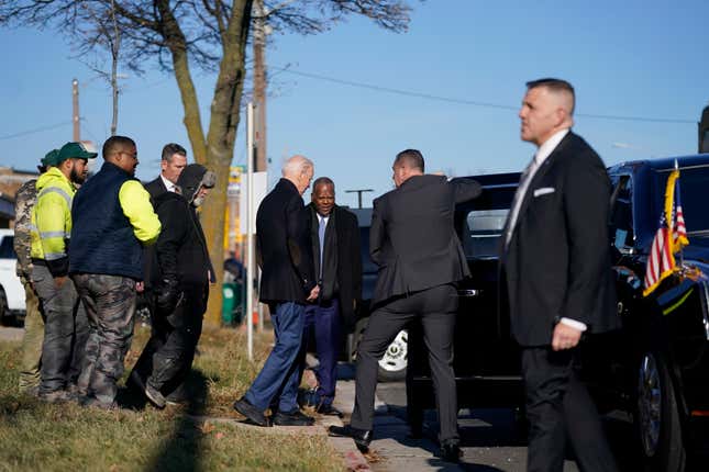 President Joe Biden walks to his motorcade after visiting Hero Plumbing on Wednesday, Dec. 20, 2023, in Milwaukee. Rashawn Spivey, CEO of Hero Plumbing, LLC, in vest third from left, and other employees look on at left. Spivey joined Biden in the motorcade. (AP Photo/Evan Vucci)