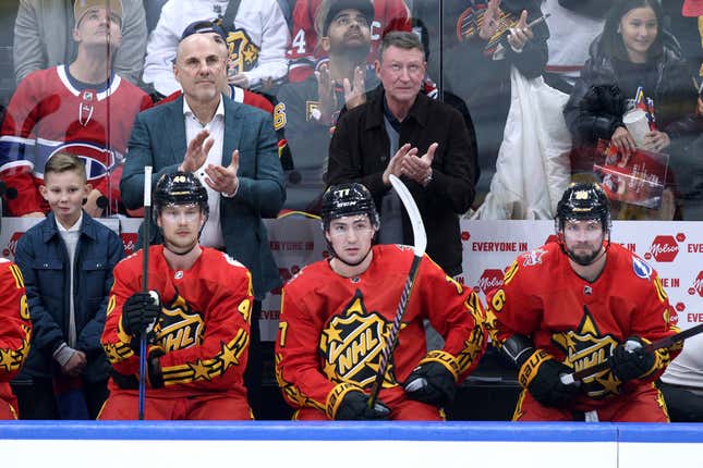 TORONTO, ONTARIO - FEBRUARY 03: Head coach Rick Tocchet of the Vancouver Canucks and NHL Hall of Fame Player Wayne Gretzky applaud while Elias Pettersson #40 of the Vancouver Canucks, Frank Vatrano #77 of the Anaheim Ducks and Nikita Kucherov #86 of the Tampa Bay Lightning look on during the game between Team Matthews and Team Hughes during the 2024 Honda NHL All-Star Game on February 03, 2024 in Toronto, Ontario. (Photo by Cole Burston/Getty Images)