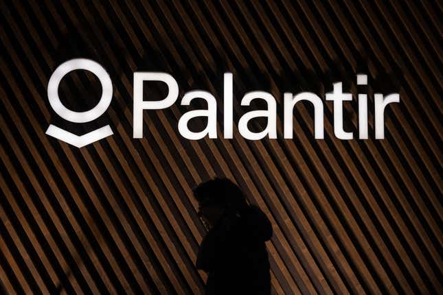 shadow of a woman walking past the Palantir logo on a building