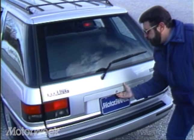 An image from the Motorweek retro review of the Renault Medallion with a tester opening the hatch of the wagon.