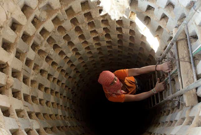 A Palestinian smuggler climbs down into a tunnel, temporarily closed by Hamas forces, beneath the Egyptian-Gaza border in Rafah in the southern Gaza Strip April 14, 2010. Israel wants to close down the smuggling tunnels between Egypt and the Gaza Strip, but the tunnelers have become so good it's now possible to drive a car through them, literally.