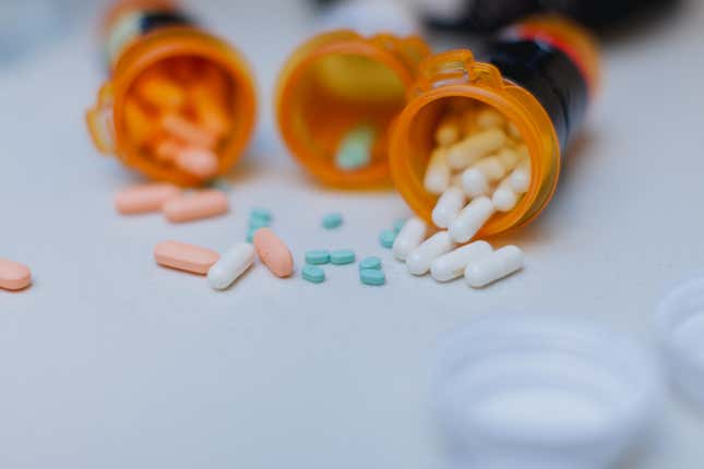 Pills are displayed with open pill bottles on top of a white counter top in the kitchen.