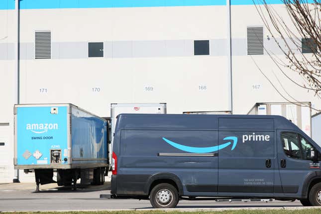 Prime trucks and a van outside a fulfillment center