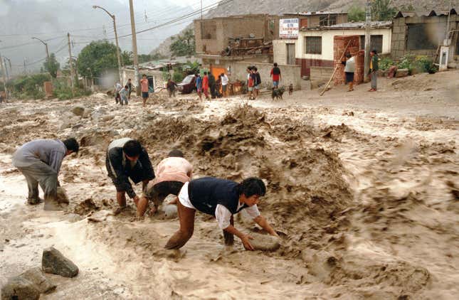 Villagers from the district of Huachipa try to slow down a mudslide by putting stones on the pavement February 5, 2002 outside Lima, Peru.