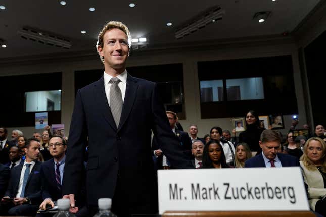 Mark Zuckerberg standing with his back turned to people behind him, a Mr. Mark Zuckerberg name card is in the forefront