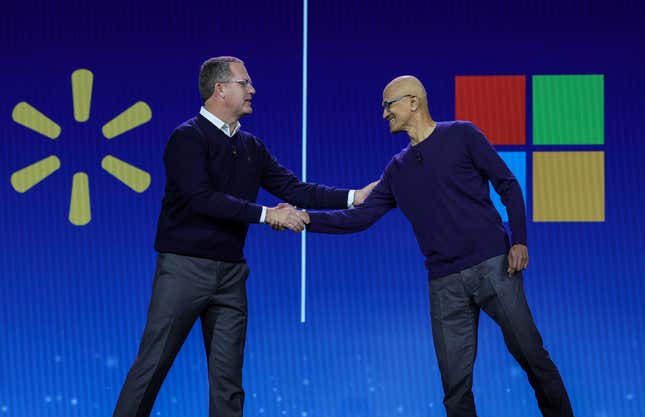 DougMcMillonserrant la main de SatyaNadella, tous deux se tiennent derrière une toile de fond devant les logos Walmart et Microsoft.