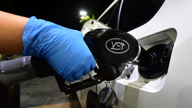 Someone wearing a plastic glove fills their car at a gas station 