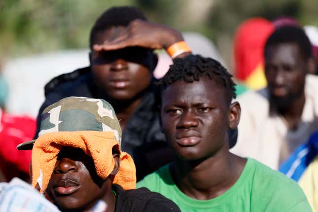 People sit outside a migrants reception center in the Lampedusa Island, Italy, Friday, Sept. 15, 2023. Thousands of migrants and refugees have landed on the Italian island of Lampedusa this week after crossing the Mediterranean Sea on small unseaworthy boats from Tunisia, overwhelming local authorities and aid organizations. (Cecilia Fabiano/LaPresse via AP)