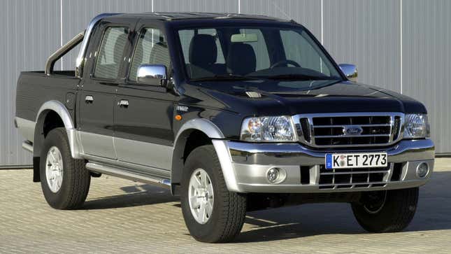 A photo of a black and silver Ford Pickup parked outside a shed. 