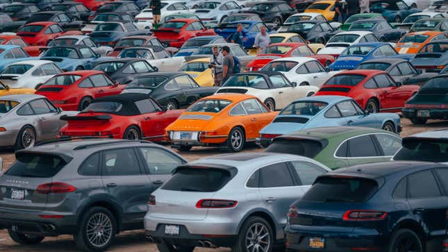 A bright orange classic 911 stands out in the center of lots of other Porsche models