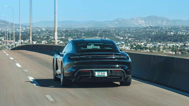 Rear view of a black 2025 Porsche Taycan sedan driving on the highway