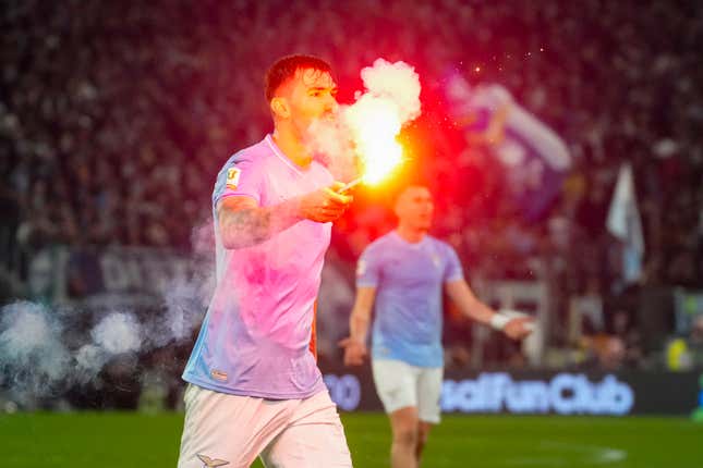 Lazio&#39;s Alessio Romagnoli holds a flare which was thrown onto the pitch during the quarterfinal Italian Cup soccer match between Lazio and Roma at Rome&#39;s Olympic Stadium, Wednesday, Jan. 10, 2024. (AP Photo/Gregorio Borgia)