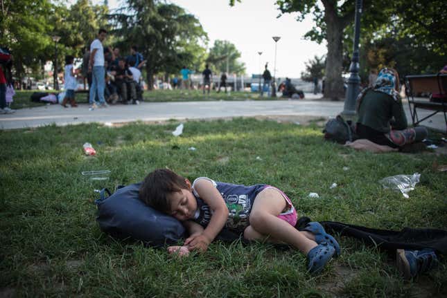 An Afghan child naps in ‘Afghan Park’ as asylum-seekers around him seek out smugglers.