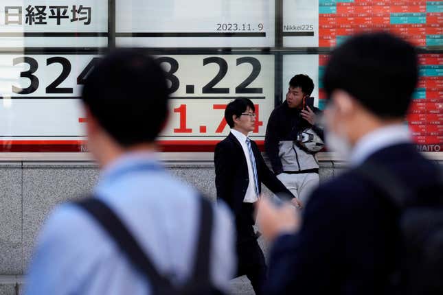 People walk past an electronic stock board showing Japan&#39;s Nikkei 225 index at a securities firm Thursday, Nov. 9, 2023, in Tokyo. Shares have fallen in Asia after a another mixed close as Wall Street recalibrates following recent big swings. (AP Photo/Eugene Hoshiko)