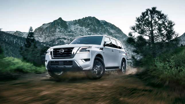 A white Nissan Armada drives through a forrest. 