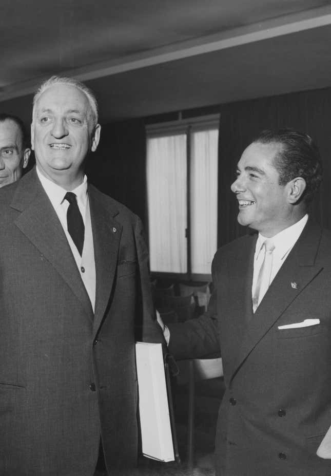 Italian race car driver and businessman Enzo Ferrari (left) with French racing driver Jean Behra (right), who is moving to the Ferrari team, circa 1958.