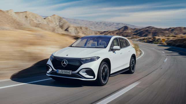 White, lozenge-shaped electric SUV drives on a curvy desert road.