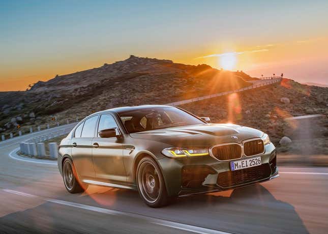 Un BMW M5 CS conduciendo por una hermosa carretera de montaña frente a un atardecer