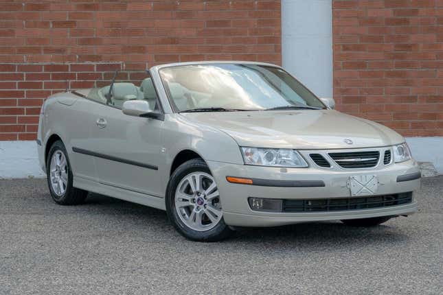 Swedish racing beige convertible parked in front of brick wall.