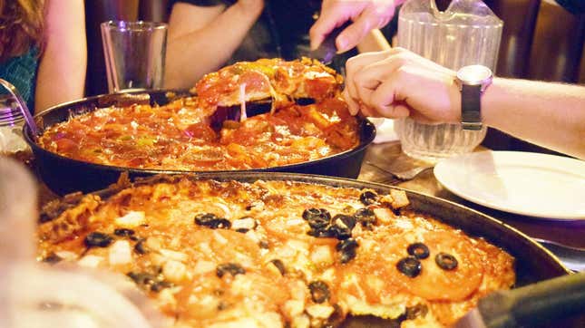 hands serving deep dish pizza