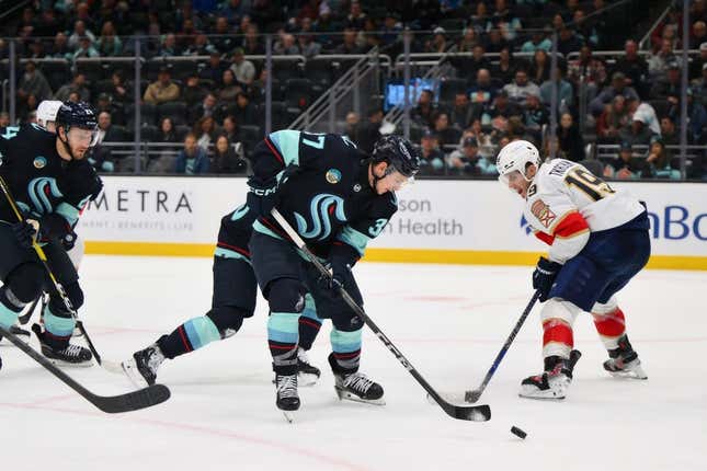 Dec 12, 2023; Seattle, Washington, USA; Seattle Kraken center Yanni Gourde (37) clears the puck away from Florida Panthers left wing Matthew Tkachuk (19) during the third period at Climate Pledge Arena.