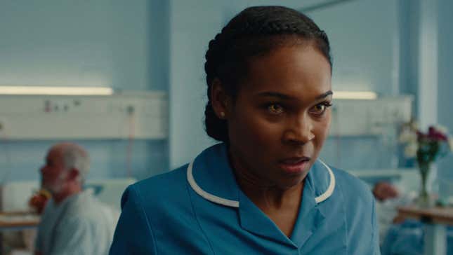 A Black woman in a nurse's uniform and a hospital setting has glowing yellow eyes.