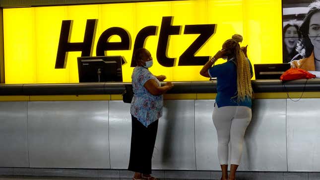 Two people standing at the hertz Rental car counter