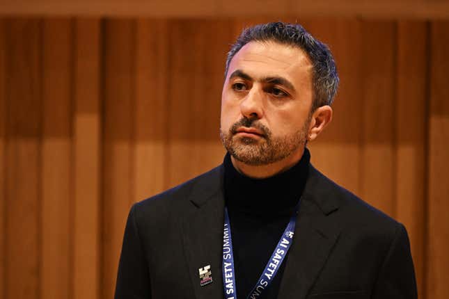 Mustafa Suleyman wearing a black turtleneck and an AI Safety Summit lanyard