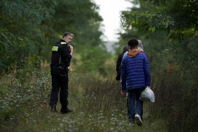 Federal Police officer Frank Malack escorts a group of migrants who illegally crossed the border from Poland into Germany during a patrol in a forest near Forst southeast of Berlin, Germany, Wednesday, Oct. 11, 2023. (AP Photo/Markus Schreiber)