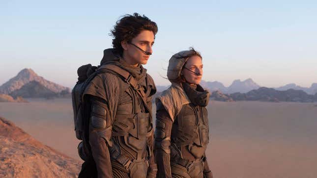 An image from Dune's 2021 adaptation has Timothée Chalamet's Paul Atreides and Rebecca Ferguson's Lady Jessica in their stillsuits staring across the desert planet of Arrakis.