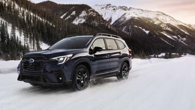 Une Subaru Ascent noire conduisant dans la neige devant des montagnes