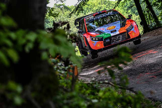 A rally Hyundai i20N catching air on a muddy circuit