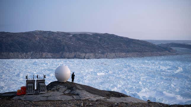 A person stands next to an antenna at the Helheim glacier in Greenland.