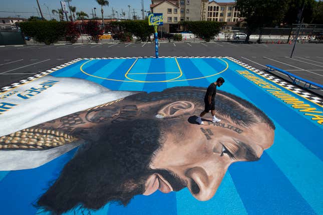 Mural artist Gustavo Zermeno Jr. walks on a basketball court mural he dedicated to slain rapper Nipsey Hussle in Los Angeles.