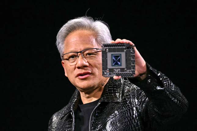 Jensen Huang holding up a chip while speaking and wearing a shiny crocodile leather jacket