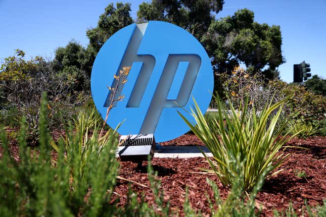 close up of blue hp logo sitting in red mulch, surrounded by little green plants