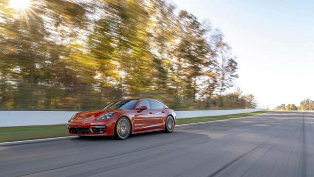 Une Porsche Panamera orange magma roulant sur une piste de course devant des arbres