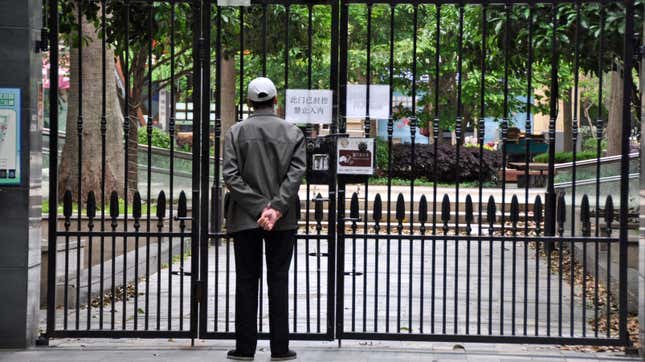 A person stands behind the closed gate of a housing complex in Shanghai on April 27, 2022, as the COVID-19 lockdown continues in the Chinese city for a month.
