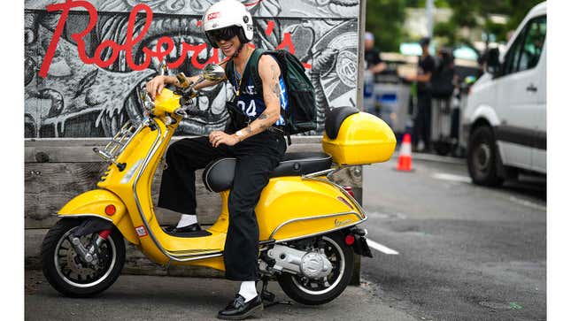 Una foto de una persona sentada en un scooter amarillo. 