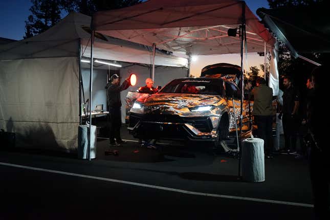 Camouflaged SUV sits on jackstands as mechanics ready it for a record attempt at Pikes Peak.