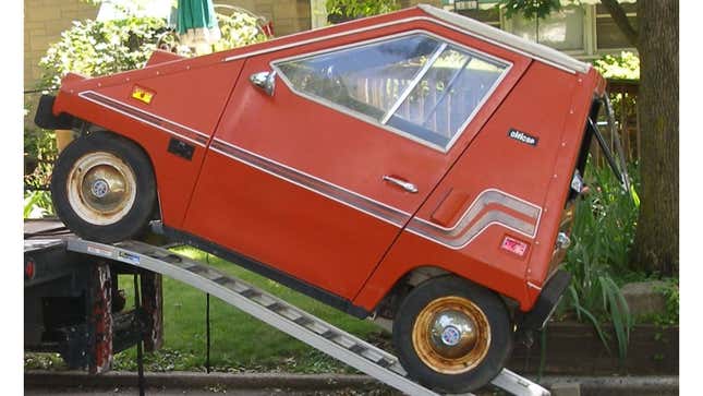 A photo of a red CitiCar microcar. 