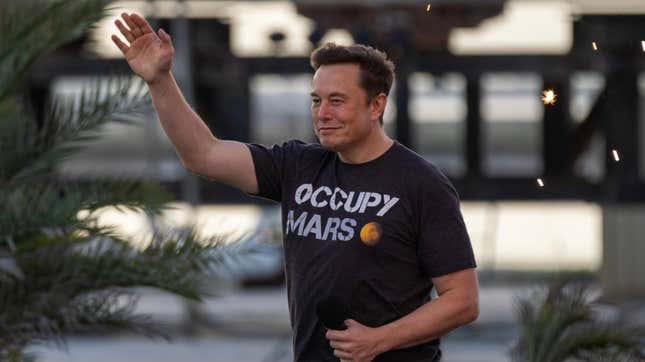 Elon Musk smiles and waves.