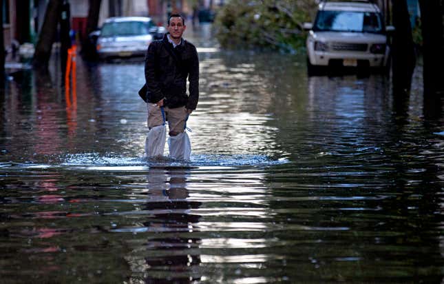 FILE - David Bagatelle walks through high water in Hoboken, N.J., Oct. 31, 2012, in the wake of Superstorm Sandy. A decade after they were first envisioned in the aftermath of Superstorm Sandy’s destruction, two of the largest flood control projects designed to protect the densely populated cities of New Jersey that lie just outside New York City will finally get underway Wednesday, Oct. 25, 2023. (AP Photo/Craig Ruttle, File)