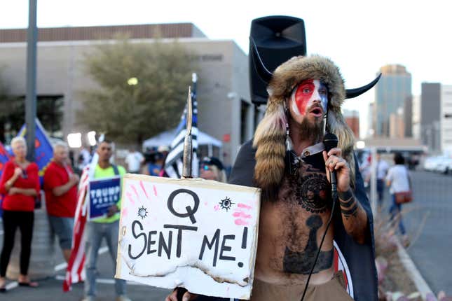 FILE - Jacob Anthony Chansley, who also goes by the name Jake Angeli, a Qanon believer speaks to a crowd of President Donald Trump supporters outside of the Maricopa County Recorder&#39;s Office where votes in the general election are being counted, in Phoenix on Nov. 5, 2020. From the Salem witch trials to fears of the Illuminati to the Red Scare to QAnon, conspiracy theories have always served as dark counter programming to the American story taught in history books. (AP Photo/Dario Lopez-Mills, File)