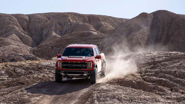 A red Ford F-150 Raptor driving on a trail. 