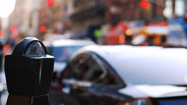 A parking meter in front of a parked sedan