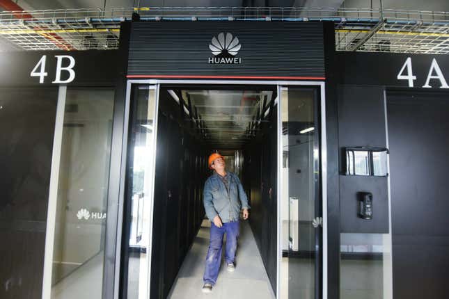 a construction worker walking between servers of a Huawei-branded supercomputer