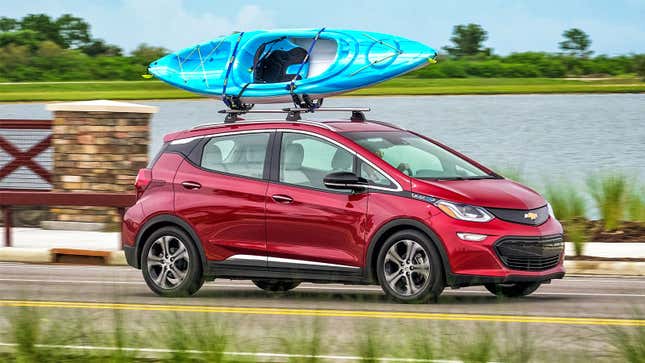 A photo of a red Chevrolet Bolt EV with a kayak on its roof. 